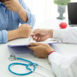 Close-up of doctor showing his patient information on a clipboard